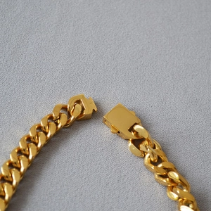 Close-up of golden heavy Cuban link chain with a polished finish and square press buckle