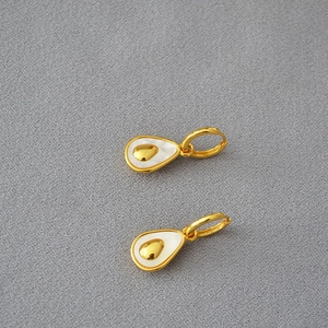 Detailed view of pear-shaped brass earrings with white mother of pearl inlay and gold accents