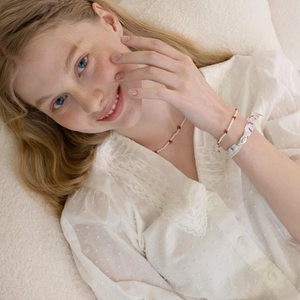 Collier en perles d'eau douce fait main avec cerises rouges sur fond de dentelle