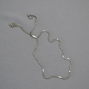 Detailed view of silver sequin chain necklace with lobster clasp and adjustable extension