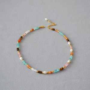 Macro shot of colorful beaded necklace with turquoise, pink, gold spacers and pearl detail