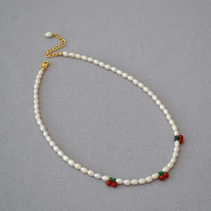 Détail du collier de perles d'eau douce avec accents de cerises rouges et fermoir doré