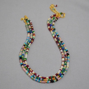 Detail of bohemian multilayered beaded necklace with colorful faceted stones and gold clasp