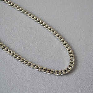 Macro shot of silver polished Cuban link chain with detailed interlocking metal rings