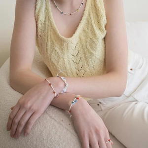 Detailed view of handmade pearl bracelet with cute red cherry charms on female model