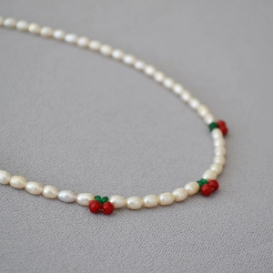 Gros plan d'un collier de perles fait main avec breloques cerises rouges et perles