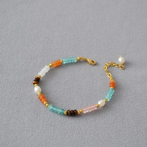 Detailed view of colorful beads and freshwater pearls on a gold necklace chain