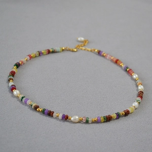 Dettaglio di perline colorate con perle d'acqua dolce e distanziatori dorati sulla collana