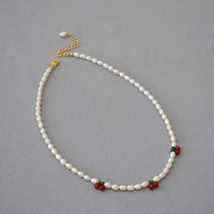 Collier de perles fait main avec perles cerises rouges et chaîne d'extension dorée sur gris