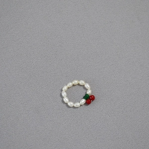 Minimalist freshwater pearl stretch ring with red cherry bead design on textured background