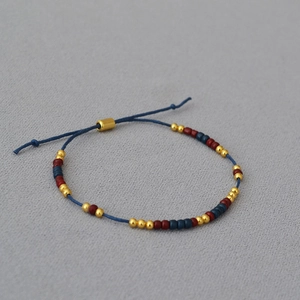 Handmade beaded string bracelet with minimalist gold, red and navy blue beads