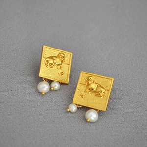 Détails de boucles d'oreilles teckel vintage avec perles sur fond de tissu gris