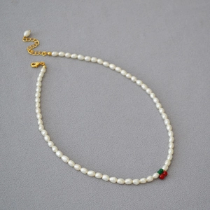 Détail du collier de perles d'eau douce avec pendentif cerise et fermoir doré