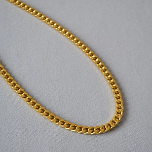 Close-up of a high-quality shiny gold plated Cuban link necklace with flat chain structure