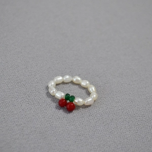 Detail of freshwater pearl elastic ring featuring a red cherry design on grey surface