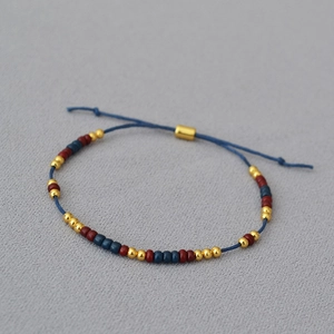 Detail of adjustable beaded bracelet with blue cord and gold metallic accents