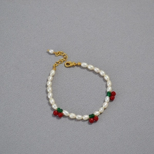 Close-up of fresh pearl bracelet with red cherry beads and golden adjustable clasp