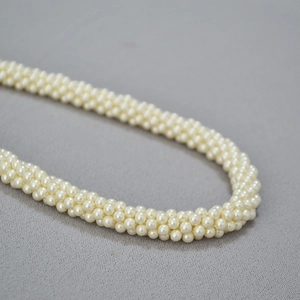 Détail macro d'un collier multicouche en perles tressées à la main pour tenue de soirée chic