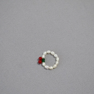 Close-up of minimalist beaded ring with freshwater pearls and red cherry charm detail