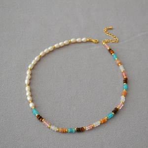 Detail of asymmetric necklace featuring freshwater pearls and colorful gemstones