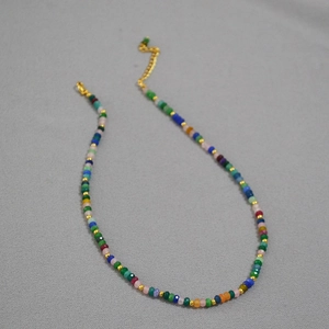 Colorful Bohemian beaded necklace with faceted stones and gold spacers on gray background