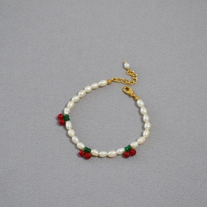 Detail of freshwater pearl bracelet featuring cute red cherry charms and golden clasp