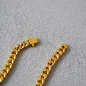 Detailed close-up of golden Cuban link necklace with industrial rectangular buckle