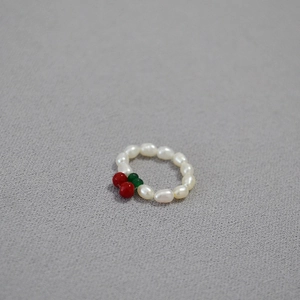 Detail of red cherry freshwater pearl ring with white beads and green leaves