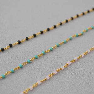 Detailed close-up of delicate gold beaded necklaces with black, turquoise and pink gems