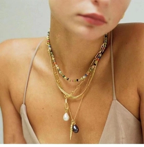Detail of layered bohemian necklace with colorful beads, golden chains, and pearl charms