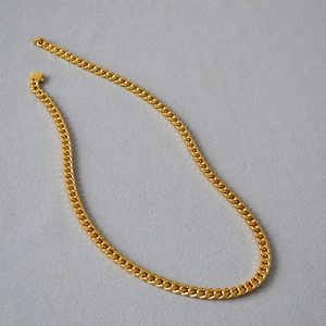 Close-up of golden stainless steel Cuban chain necklace with high-polished flat links