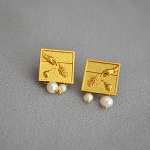 Détails de boucles d'oreilles vintage dorées avec motifs gaufrés et perles d'eau douce