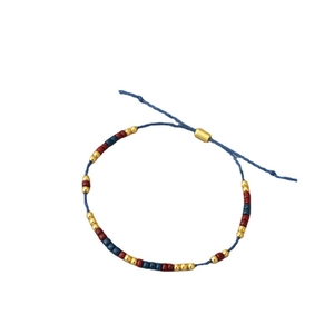 Minimalist hand-woven beaded bracelet with blue string and adjustable gold metal closure