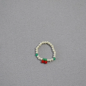 Detailed view of handmade stretch ring with silver beads and small red cherry pattern