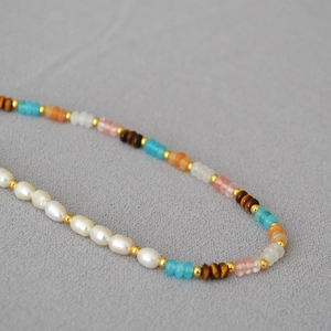 Macro detail of mixed freshwater pearls and colorful disc beads on a layered necklace