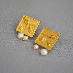 Détail macro de boucles d'oreilles vintage en relief doré avec perles d'eau douce