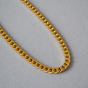Close-up of polished gold Cuban link chain with detailed flat interlocking links