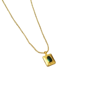 Collier en laiton doré avec pendentif en pierre verte émeraude sur fond blanc