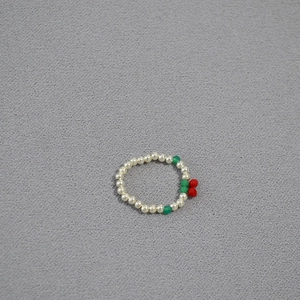 Detail showing elastic ring with white rice pearls and red cherry charm decoration