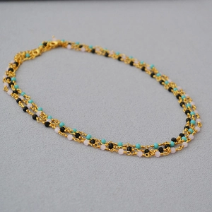 Detail of woven choker necklace with black spinel and colorful beads on gold chain