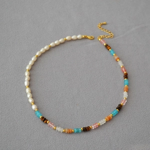Detail of freshwater pearl necklace with colorful semi-precious stone beads and gold clasp