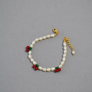 Detail of freshwater rice pearls bracelet with cute red cherry charms and gold clasp