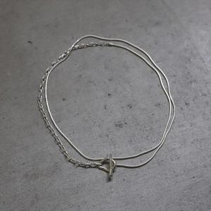 Detail of silver double-layered chain necklace featuring a minimalist OT toggle clasp