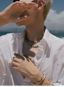 Close-up of layered colorful gemstone necklaces and baroque pearl bracelet on a model