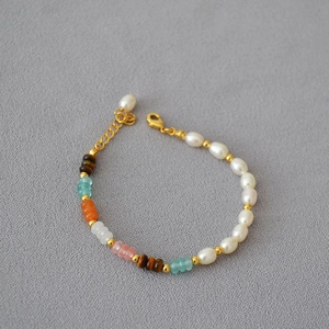 Detail of beaded necklace with freshwater pearls, tiger eye, and stones on a grey base