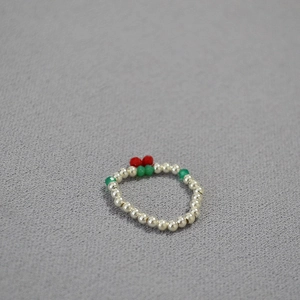 Detailed view of elastic beaded ring featuring red cherries and silver pearls