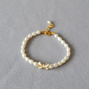 Elegantes weißes Emaille-Schleife Süßwasserperlen-Armband mit verstellbarer Goldkette