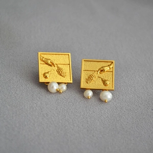 Gros plan de boucles d'oreilles carrées dorées vintage avec reliefs de raisins et perles