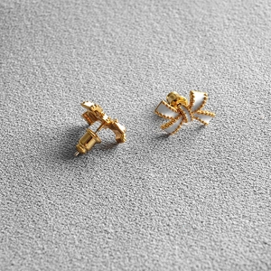 Elegant gold bow earrings with white enamel finish and beaded edges for a sweet style