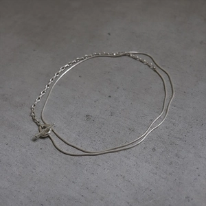 Detail view of silver double-layered chain necklace with OT toggle clasp on grey background